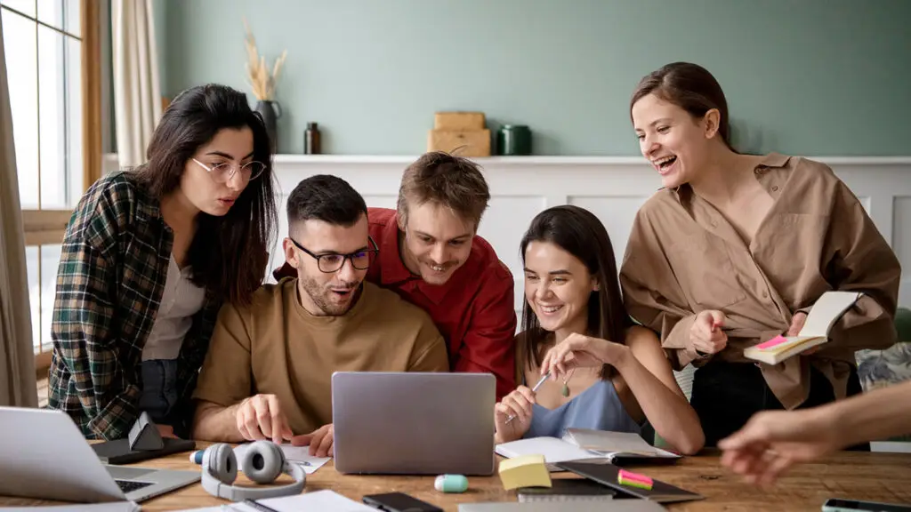 Group of young professionals collaborating around laptop for digital marketing and IT services.