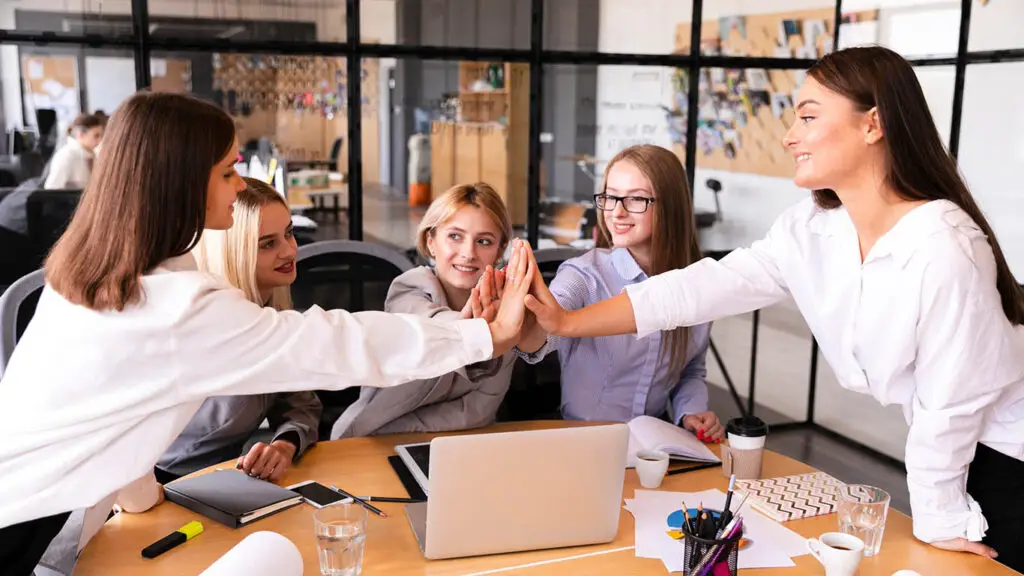 Team of business professionals celebrating success in a modern office environment.