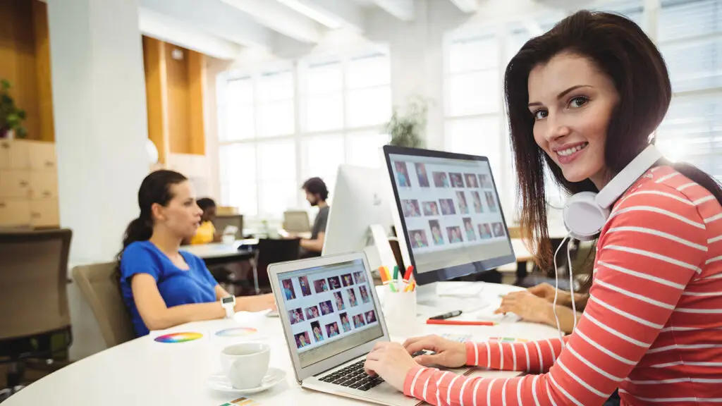 Woman smiling at computer displaying digital marketing content and website design.