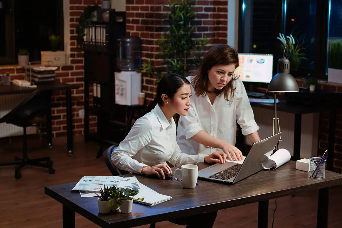 Women collaborating on laptop for branding and identity project design.